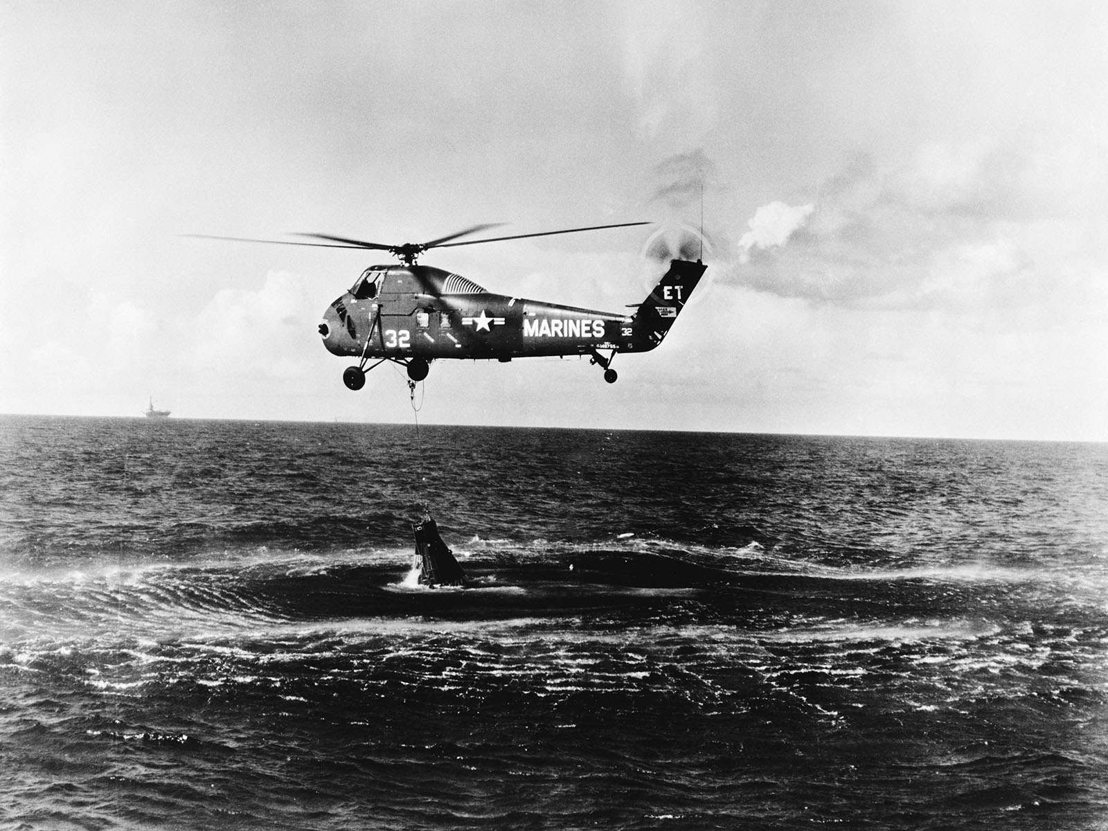 aerial photo of a rescue helicopter lifting a space capsule from the sea